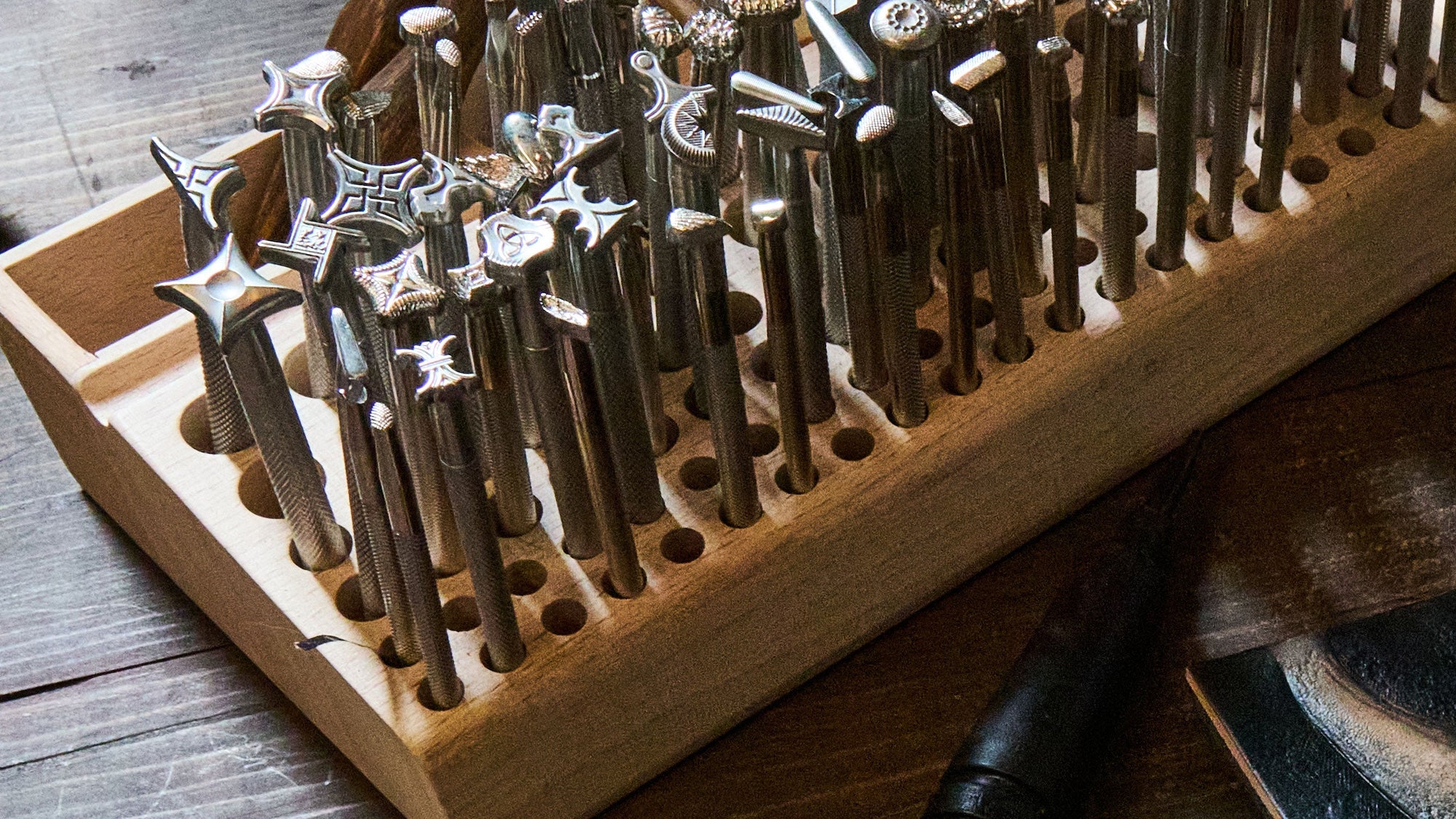 Set of metal tools in a wooden holder on a wooden surface